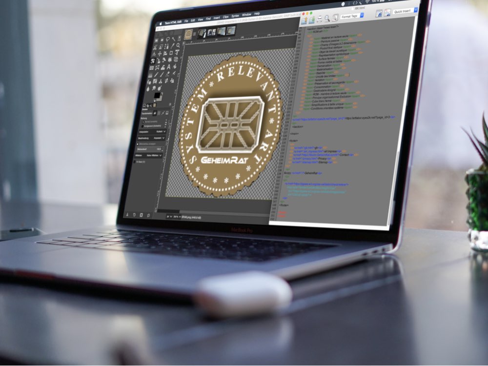 View of the screen of a laptop. On the screen you can see a gold-colored emblem opened in a graphics editor, with 'System Relevant Art' and 'GeheimRat' written on it. To the right, an html file opened in an html editor can be seen.